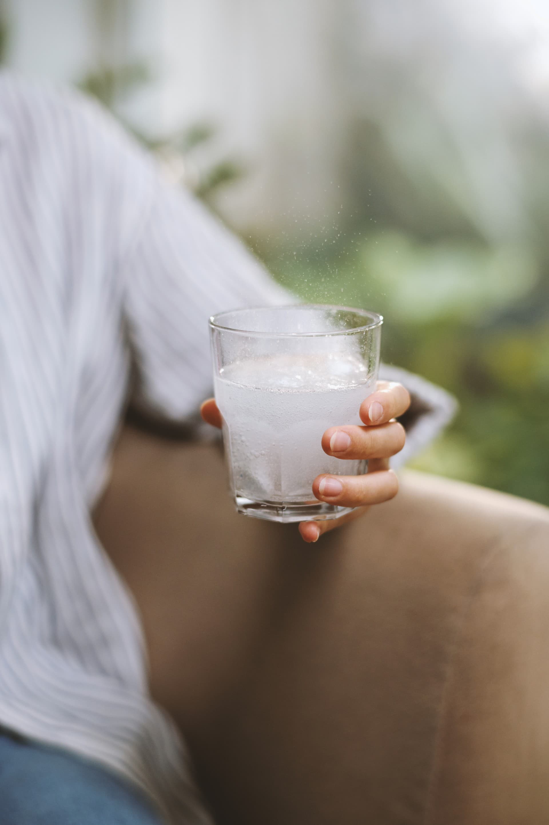 glass with dissolving fizzy tablet hand woman sitting couch